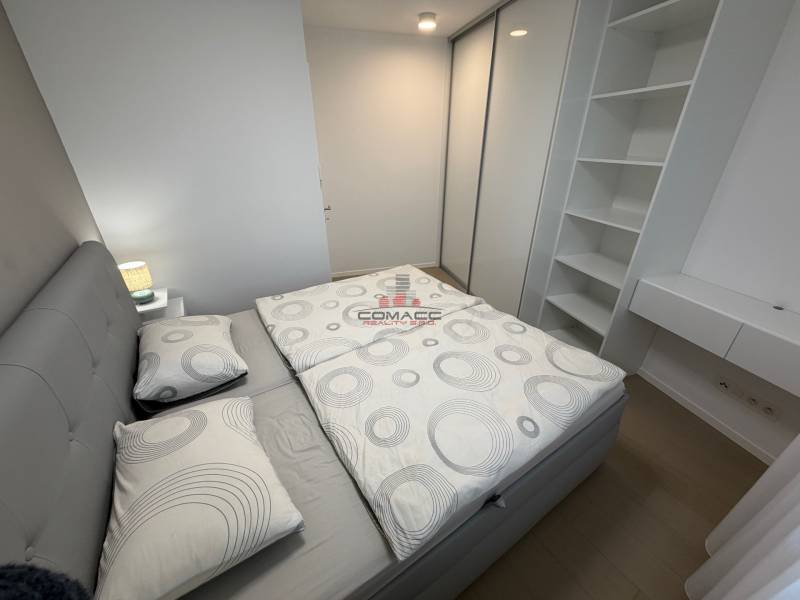Bedroom in a two-room apartment with wood-patterned flooring and practical storage spaces.