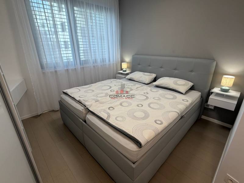 Bedroom in a two-room apartment with a bed, nightstands, and a floor with a wood decor.