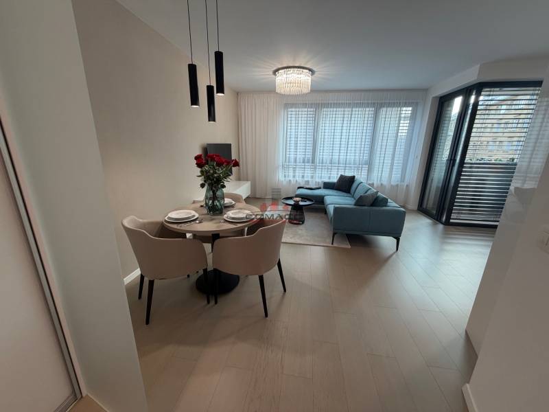 Interior of a 2-room apartment with wooden decor flooring, a dining table, and a balcony.