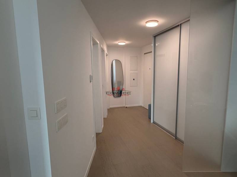 A hallway with white walls, a wooden decor floor, and a built-in wardrobe in a 2-room apartment.