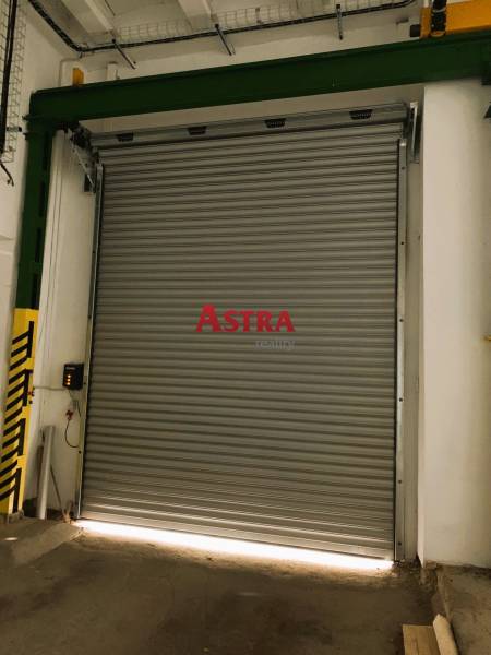 Industrial rolling door for warehouses and halls, closed, with green and yellow protective strip.