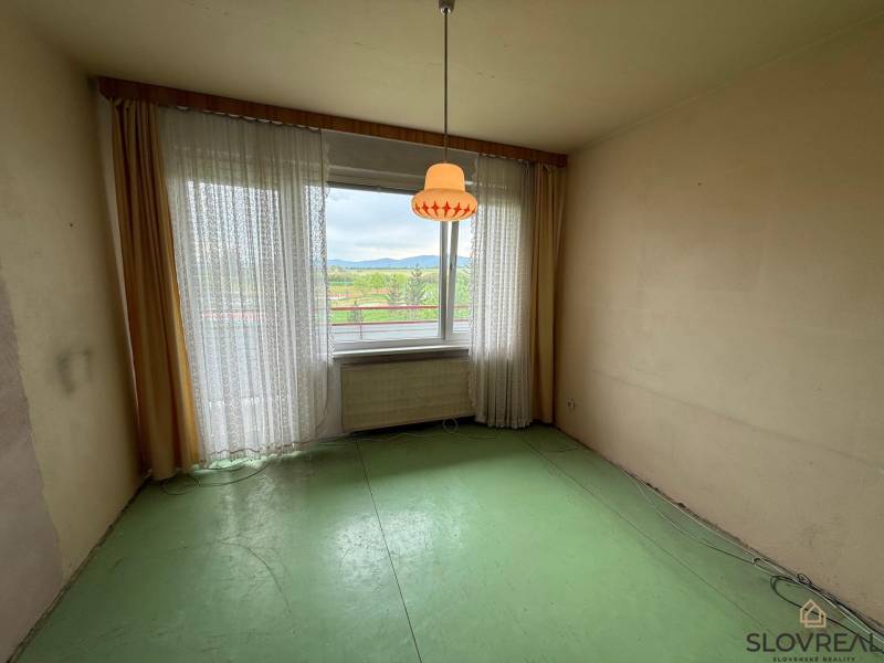 A room with a green floor and a large window in a 3-room apartment.