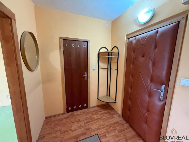 A hallway in a 3-room apartment with a wooden decor floor and decorated doors.