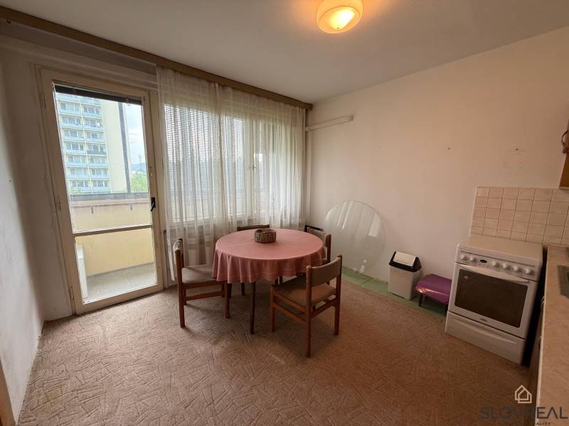 A kitchen in a 3-room apartment with a dining table, electric stove, and access to a balcony.