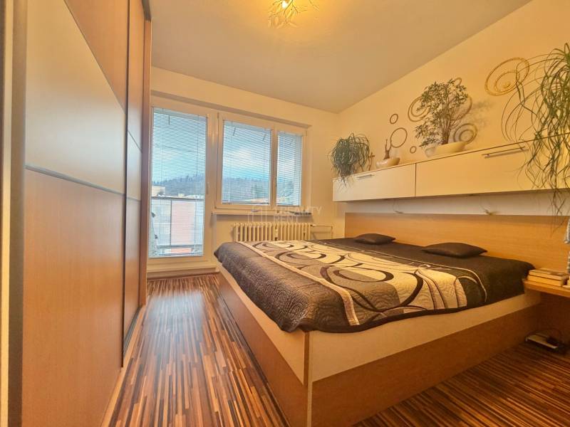 Bedroom in a 4-room apartment with a bed, built-in wardrobe, and floor with wood decor.