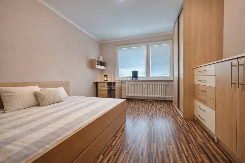 Bedroom in a 4-room apartment with wood-patterned flooring and built-in furniture.
