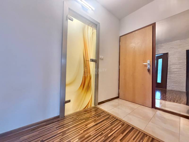 Entrance hall in a 4-room apartment with wood-patterned flooring and decorative glass doors.