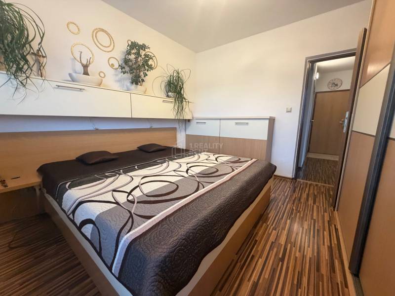 Bedroom with built-in wardrobes and a bed in a 4-room apartment with a wooden decor.