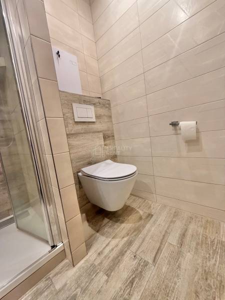 A bathroom in a 4-room apartment with a wooden decor floor and a shower corner.