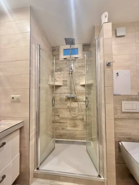 Shower enclosure in a 4-room apartment with tiles and a modern shower head.