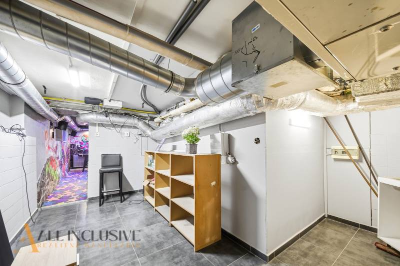 A space in a building with lots of piping, shelves, and a colorful graffiti wall.