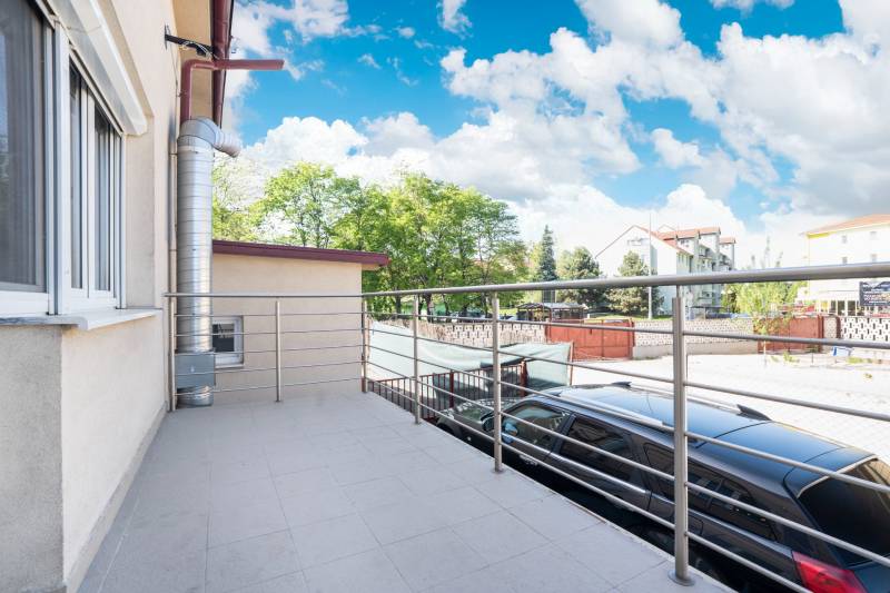 A balcony in Dunajská Streda with a view of the surrounding buildings and park.