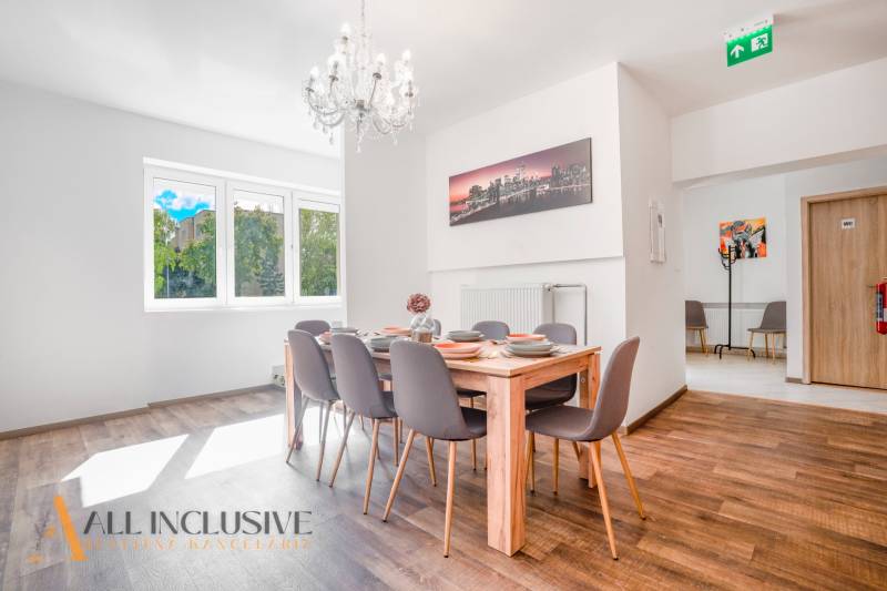 A dining room with a chandelier and wood-patterned flooring in a building.