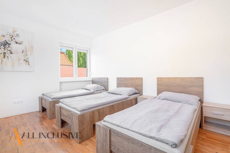 Three beds in a room with a wooden floor and a painting on the wall.