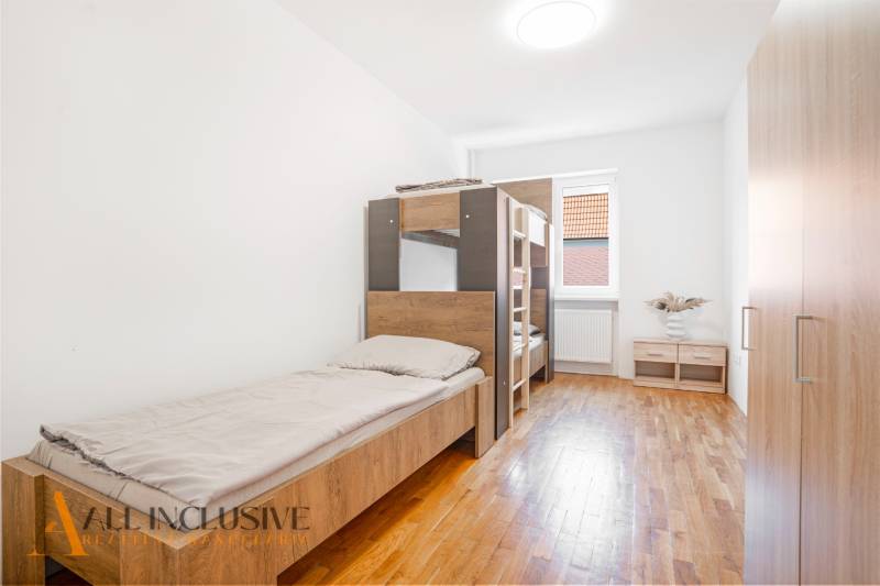 The interior of a bedroom in a building with beds and a wooden decor floor.