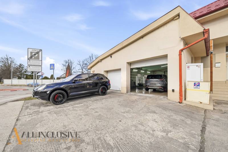 A building in Dunajská Streda with cars in front of garages and traffic signs.