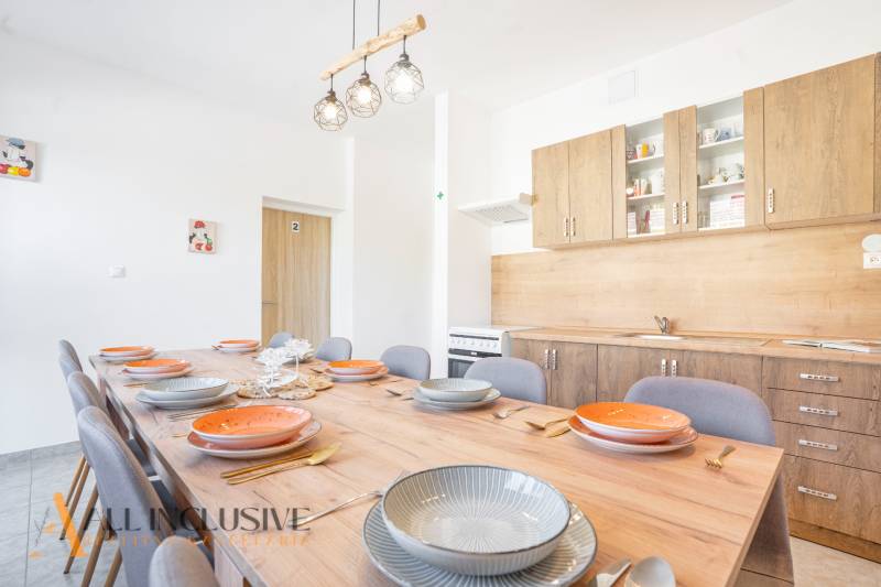 A kitchen in a building, wooden cabinets, a large table with a wooden decor floor.
