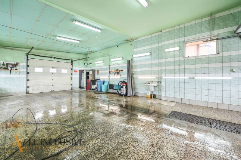 A room in a building with wet tiles, a sink, and a hose on the wall.
