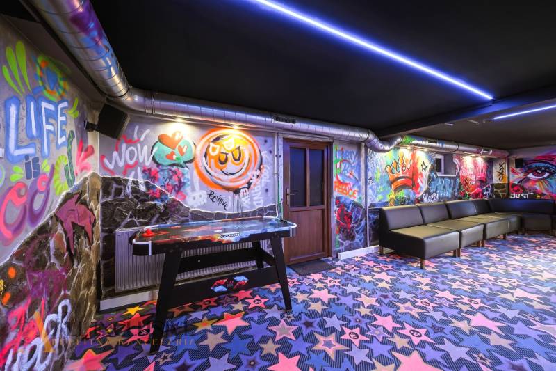 The interior of a building with graffiti on the walls, colorful carpets, and a table hockey game.
