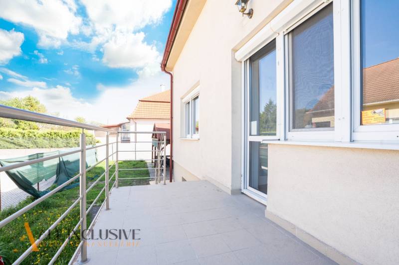 A building in Dunajská Streda with a terrace and railing, sky with clouds.