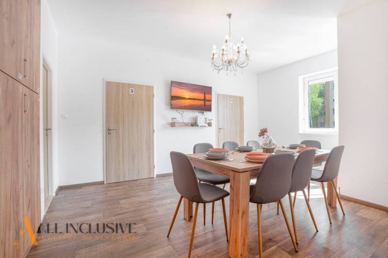 Dining room with a set table, chandelier, and wooden decor flooring in a building.