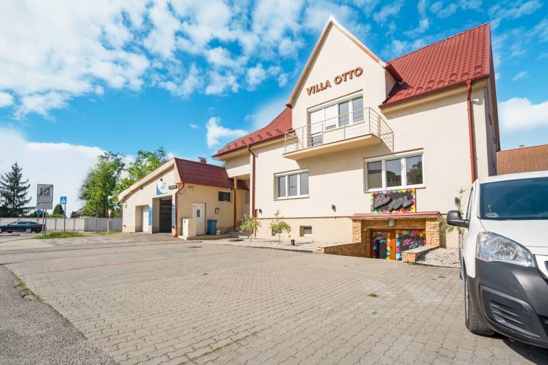 Building in Villa Otto in Dunajská Streda with a red roof and a paved parking lot.