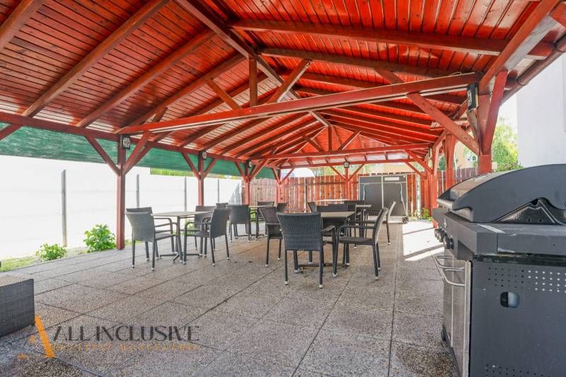 An exterior terrace of a building in Dunajská Streda with a wooden roof and a grill.