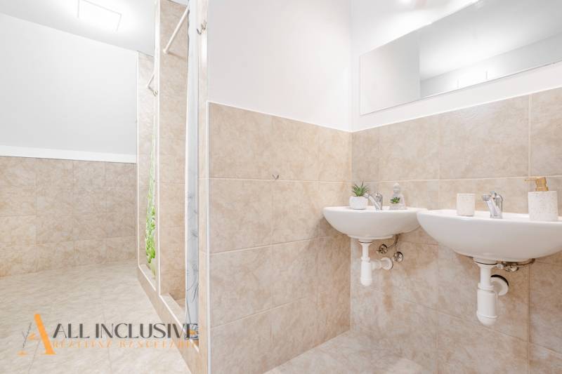 Bathroom with two sinks and a shower, decorative tiles and a mirror in the building.