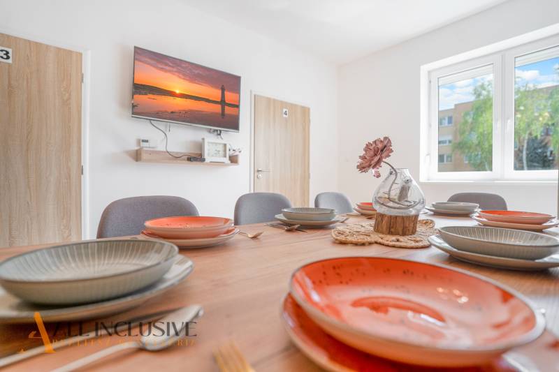 A dining room in a building with a decorative table, colorful plates, and a television on the wall.