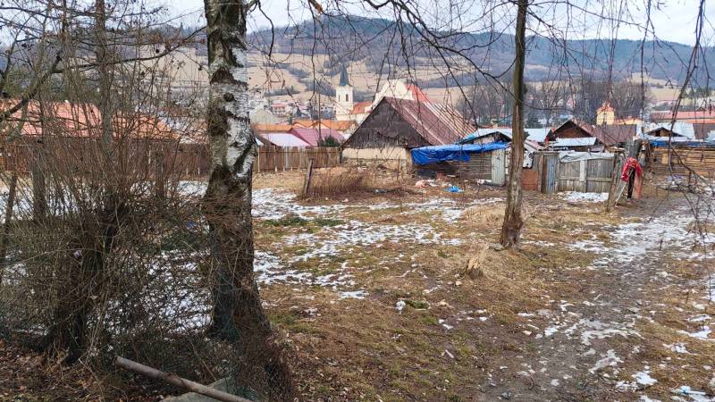 Snow-covered gardens in Nálepkovo with cottages and a view of the hills and church.