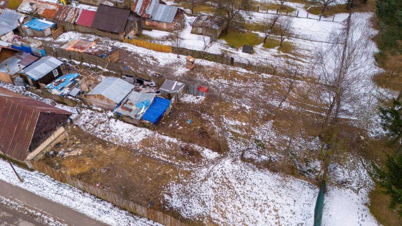 A winter garden in Nálepkovo with snow-covered cottages and trees, contrasting with the brown soil.