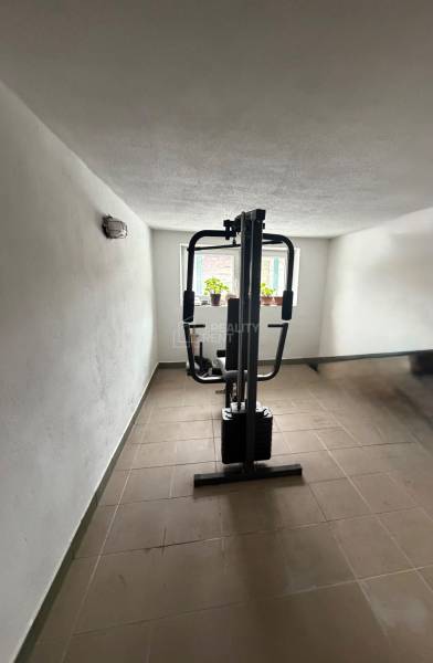 A small gym with a weight machine in a family house, lit by natural daylight.