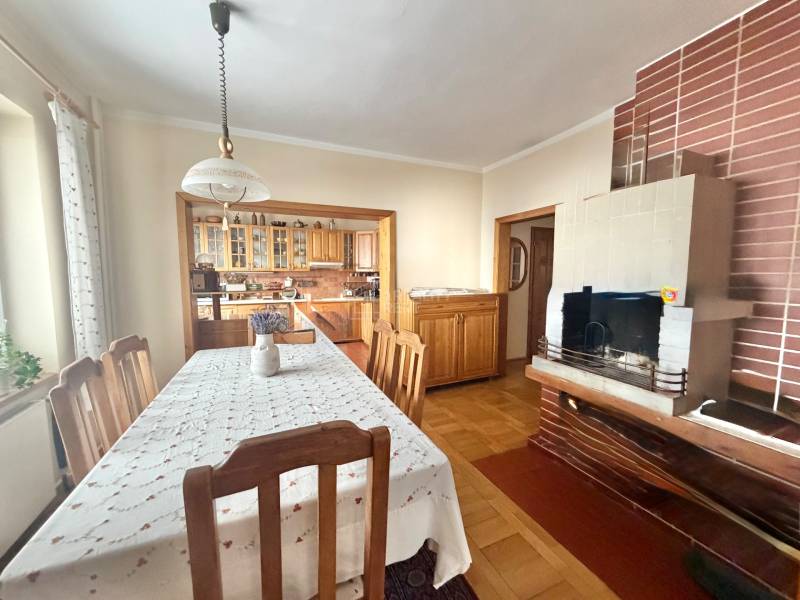 Dining room in a family house with a fireplace and kitchen, floor with wooden decor.