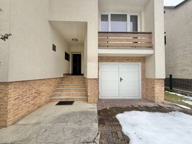 A family house in Čadečka in Čadca with stairs and a garage, remnants of snow on the driveway.