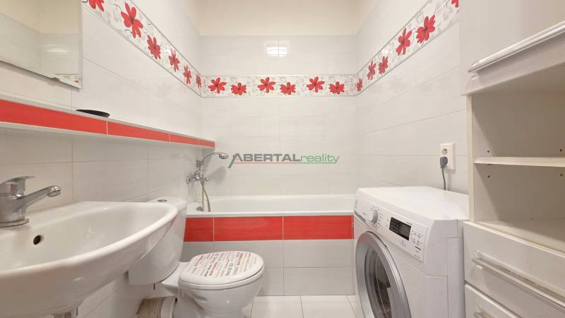 Bathroom with a bathtub, sink, and washing machine in a studio apartment.