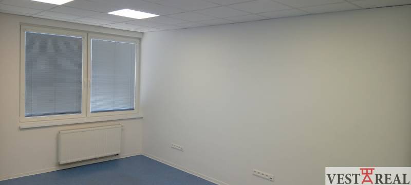 Offices with white walls and ceiling lights, containing a radiator and a large window.