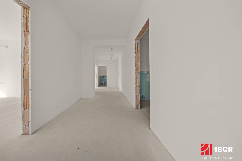 A hallway under construction in a 4-room apartment with unfinished doorways and neutral walls.