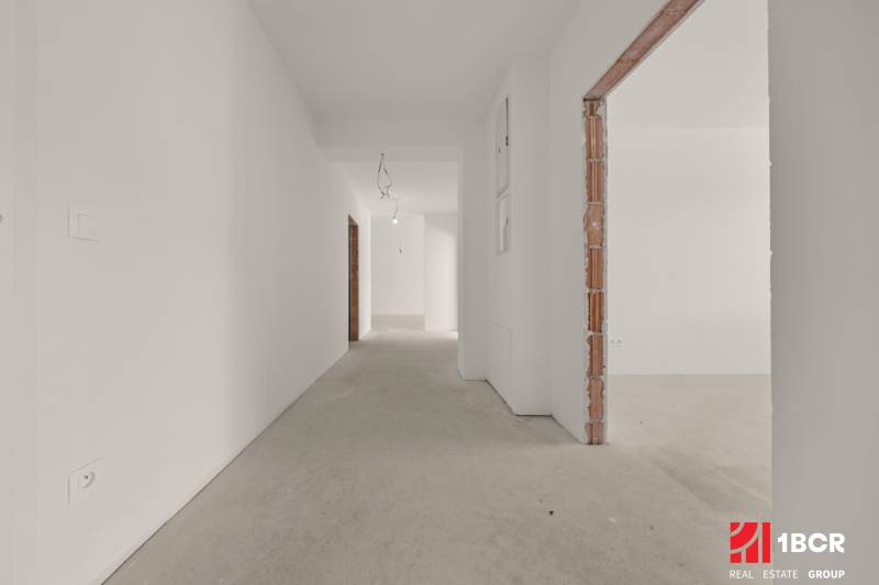 A hallway in a 4-room apartment with white walls and a concrete floor.