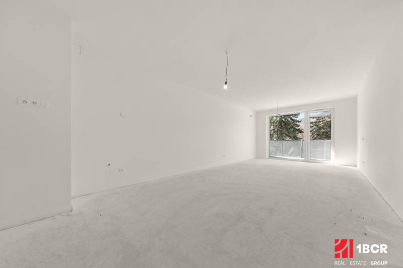 A spacious room in a 4-room apartment with a large French window and white walls.