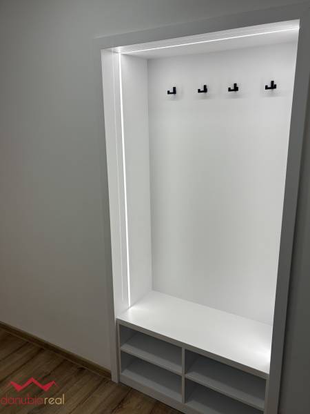 Built-in hallway wardrobe in a 3-room apartment with hooks and a floor with a wood decor.