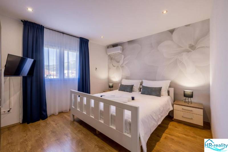 Bright bedroom with TV, air conditioning, and wood-patterned flooring in the villa.