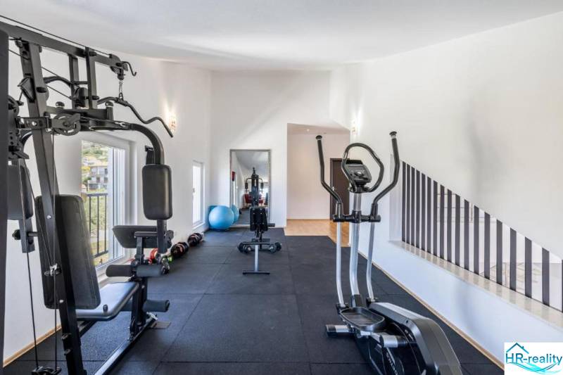 Interior of a fitness center in a villa with exercise machines and a large mirror.