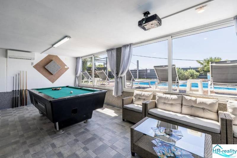 Interior of a villa with a billiard table and a view of the pool.