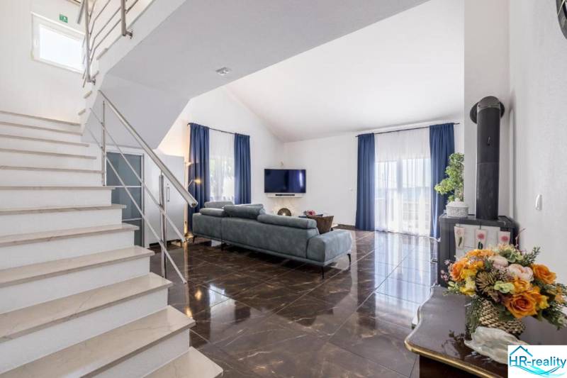 Living room of the villa with a shiny floor and blue curtains.