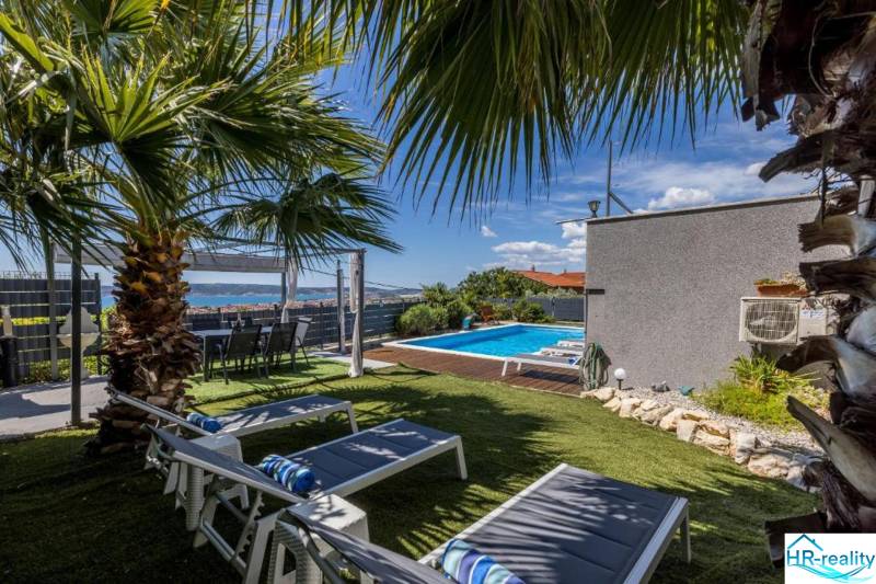 A cozy garden with a pool in a villa in Kaštela, surrounded by palm trees and loungers.