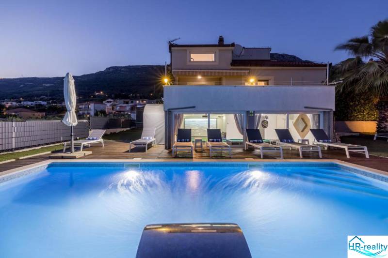 Night Villa in Kaštela with a pool, sun loungers, and a view of the mountains in the background.