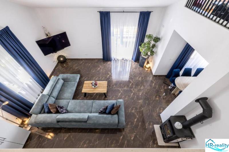 A villa with a view of the living room with a blue sofa and marble floor.