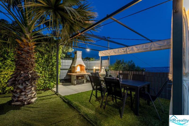 The palm garden of the villa in Kaštela with a pergola, fireplace, and table.
