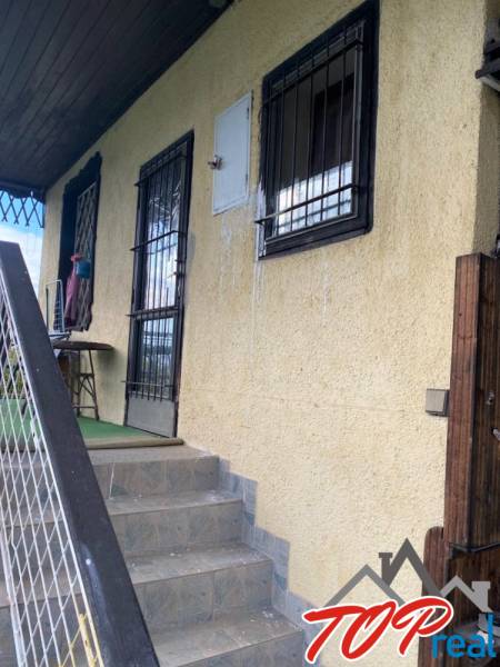 Entrance stairs and window grilles of the cottage in Vyšné Opátske, Košice, with a yellow facade.