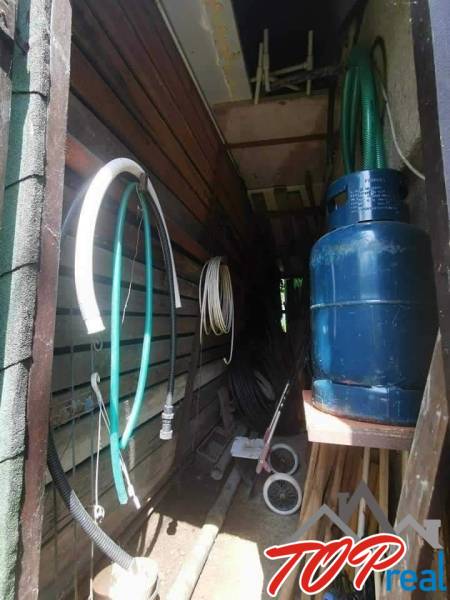 Storage space at the cottage with hoses, a gas tank, and various tools in Košice.